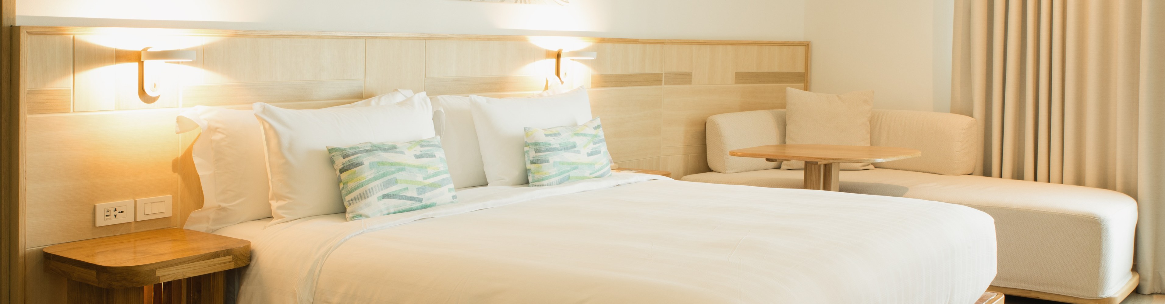 Hotel bedroom with linen curtains and a bedside lamp
