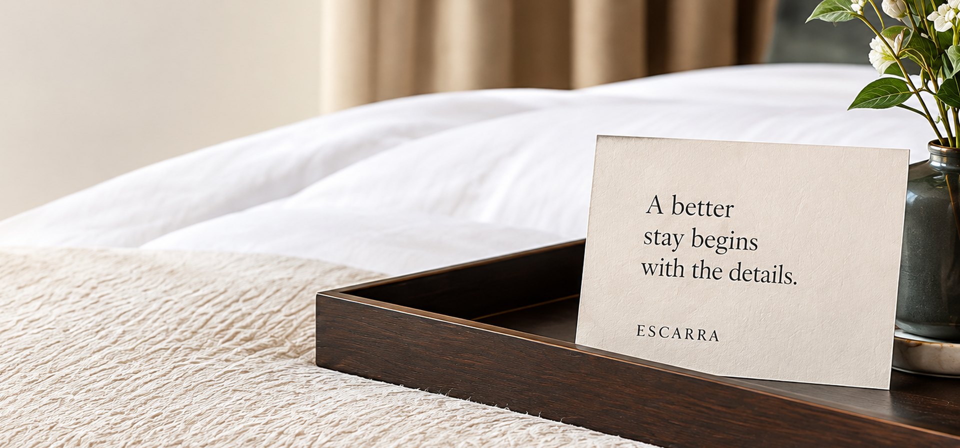 Hotel bed with an Escarra welcome card on a tray